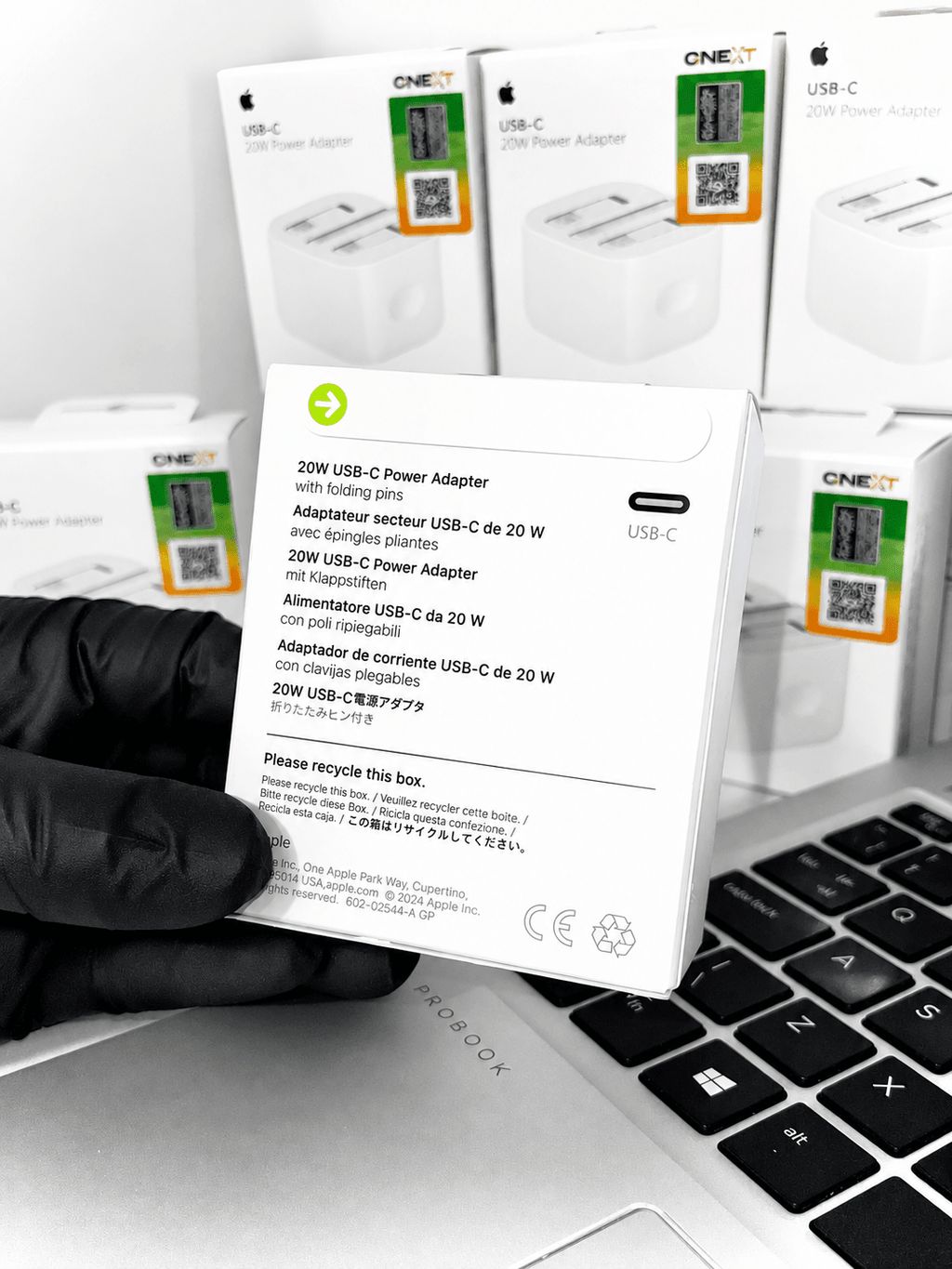 20W USB-C Power Adapters in white retail packaging next to a laptop keyboard.