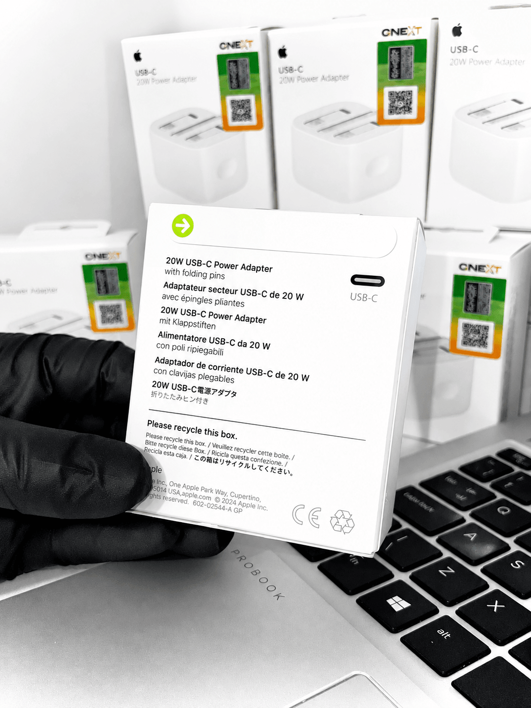 20W USB-C Power Adapters in white retail packaging next to a laptop keyboard.
