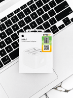Apple USB-C 20W Power Adapter packaging on a white laptop keyboard