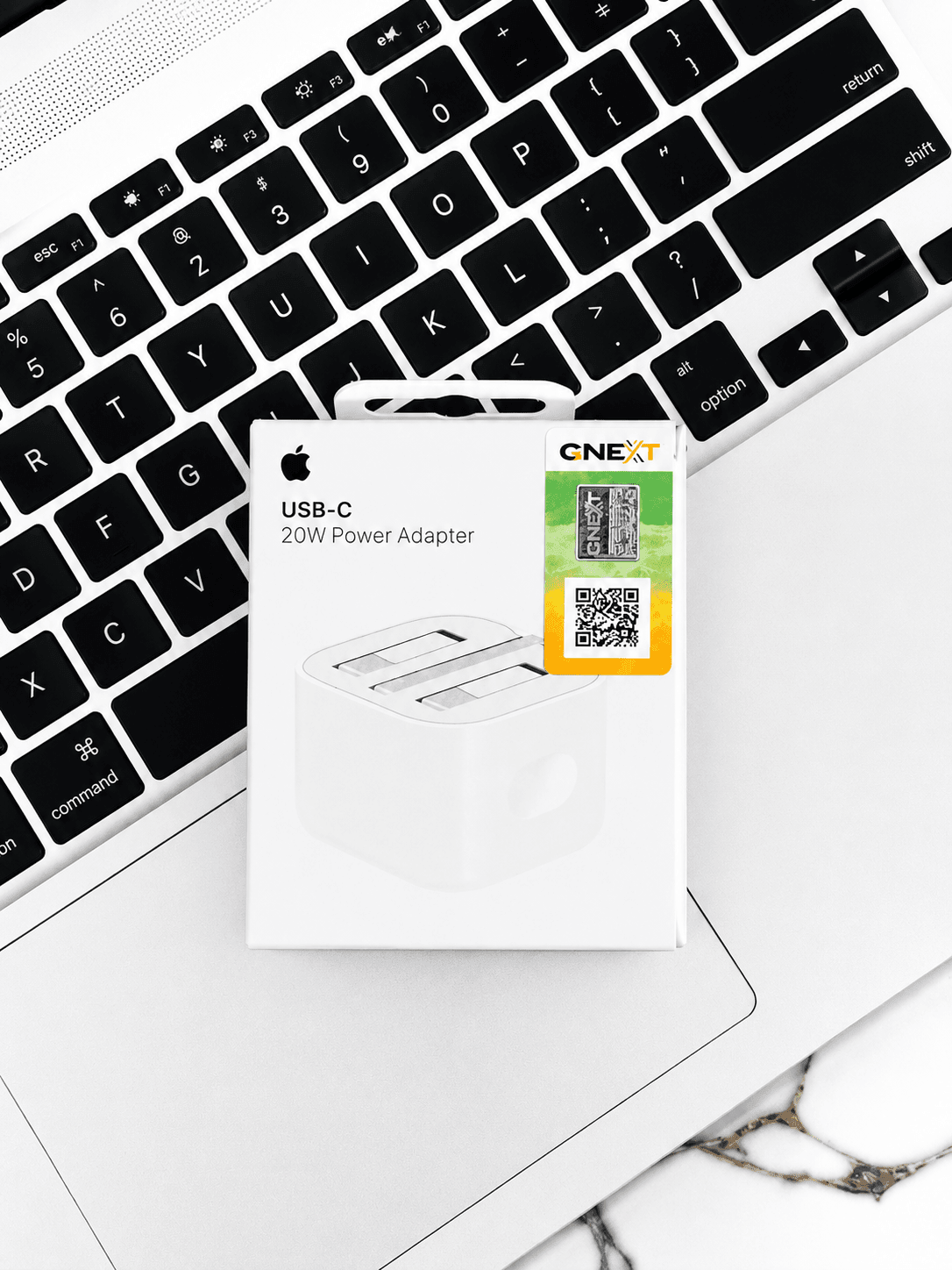Apple USB-C 20W Power Adapter packaging on a white laptop keyboard