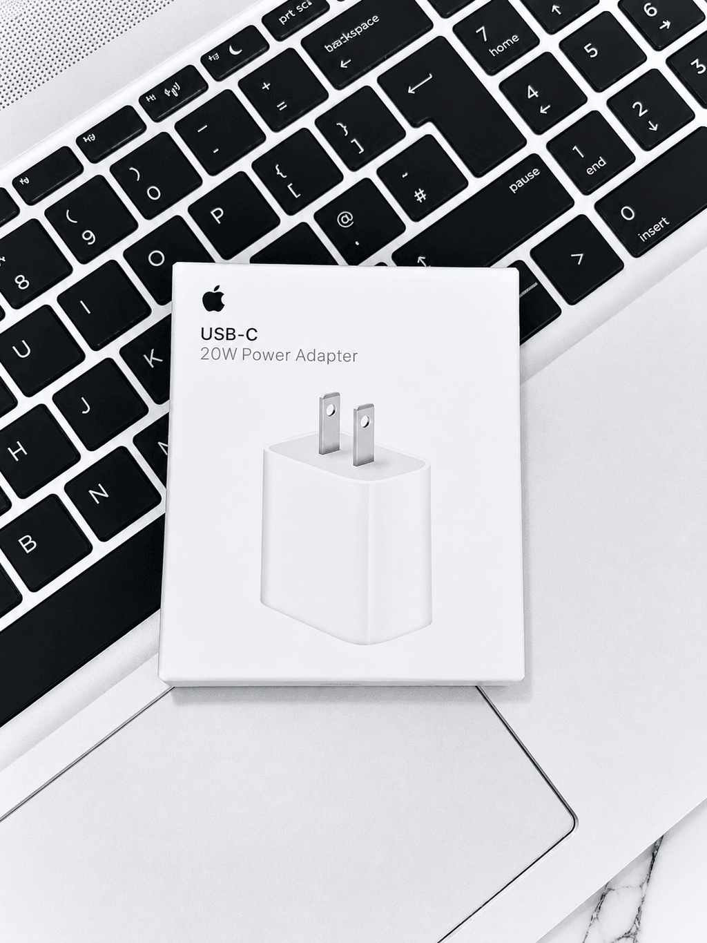 Apple USB-C 20W Power Adapter box resting on a laptop keyboard