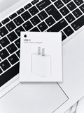 Apple USB-C 20W Power Adapter box resting on a laptop keyboard
