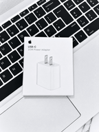 Apple USB-C 20W Power Adapter box resting on a laptop keyboard