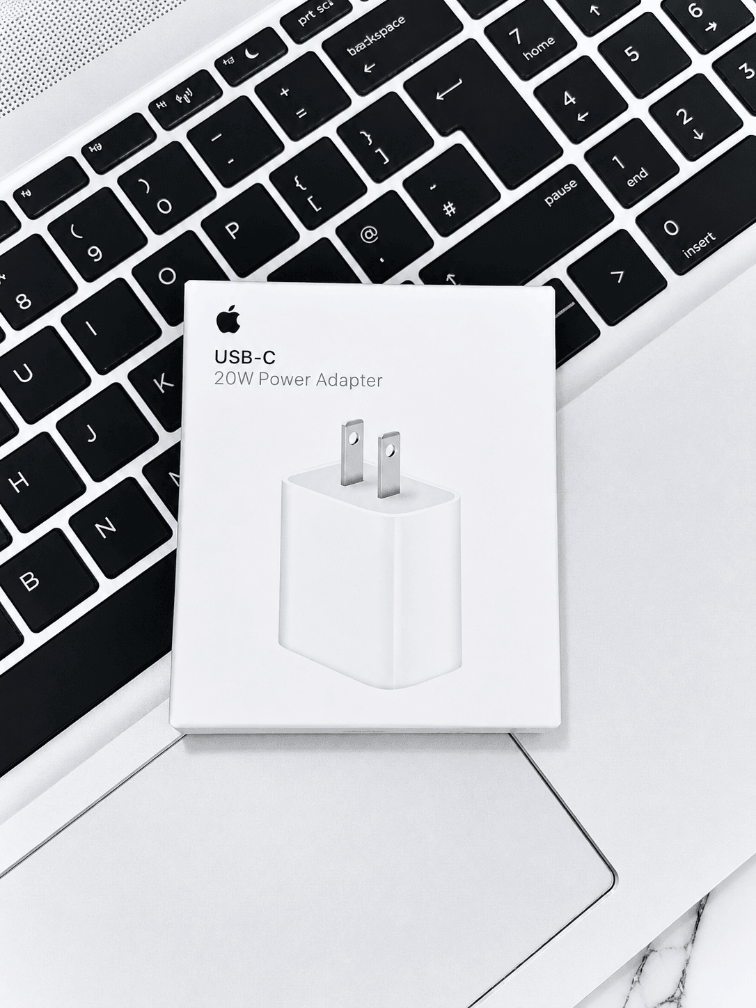 Apple USB-C 20W Power Adapter box resting on a laptop keyboard