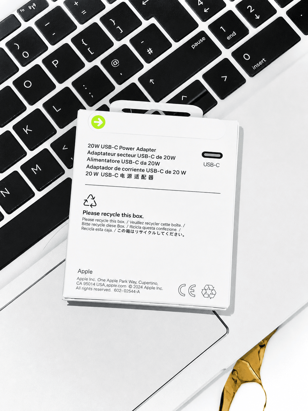 Apple 20W USB-C Power Adapter packaging resting on a laptop keyboard.