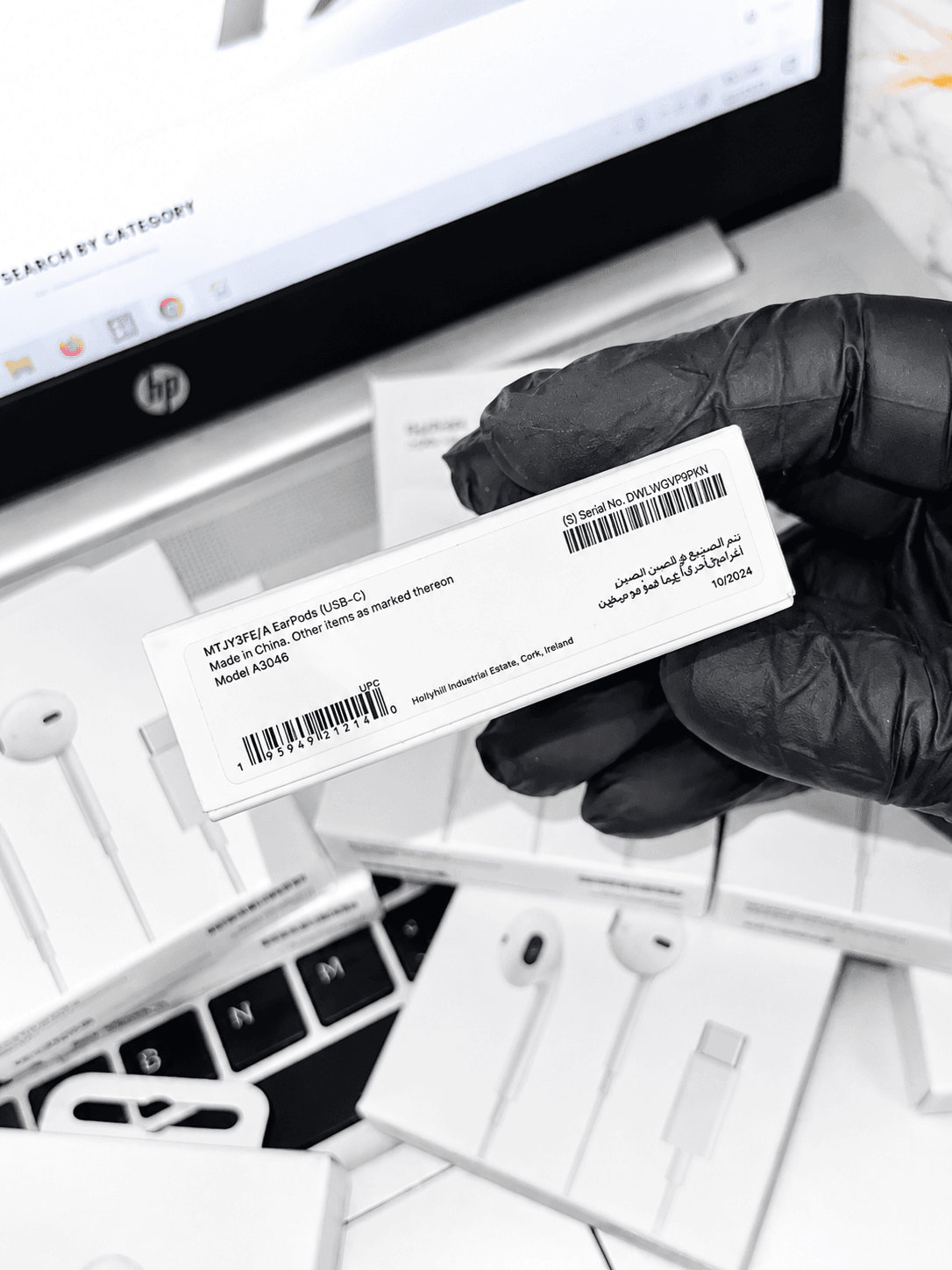Close-up of a person wearing black gloves holding a white EarPods (USB-C) product box.