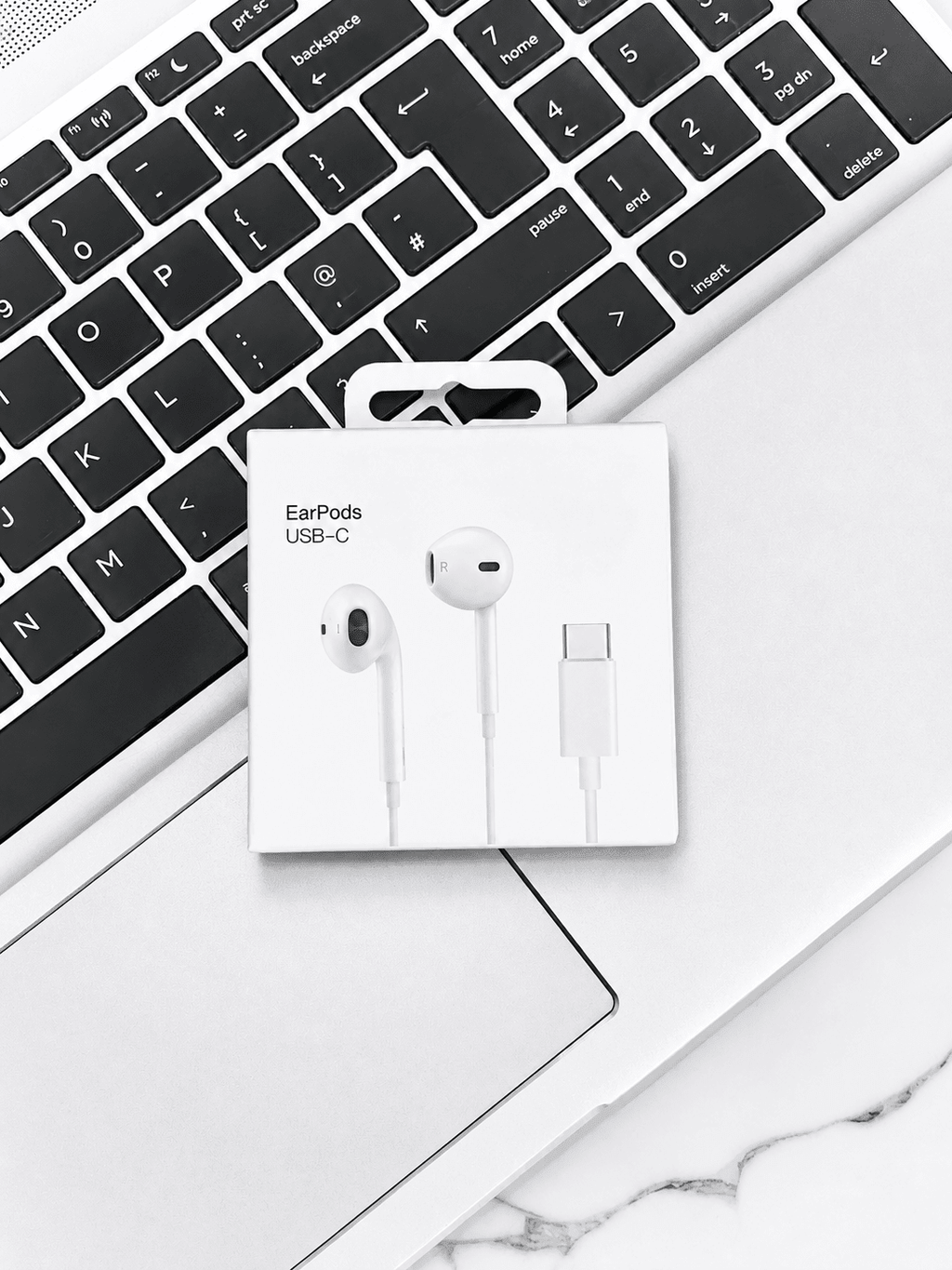 Apple EarPods USB-C headphones in packaging on a laptop keyboard.