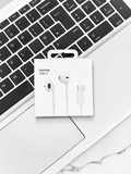Apple EarPods USB-C headphones in packaging on a laptop keyboard.
