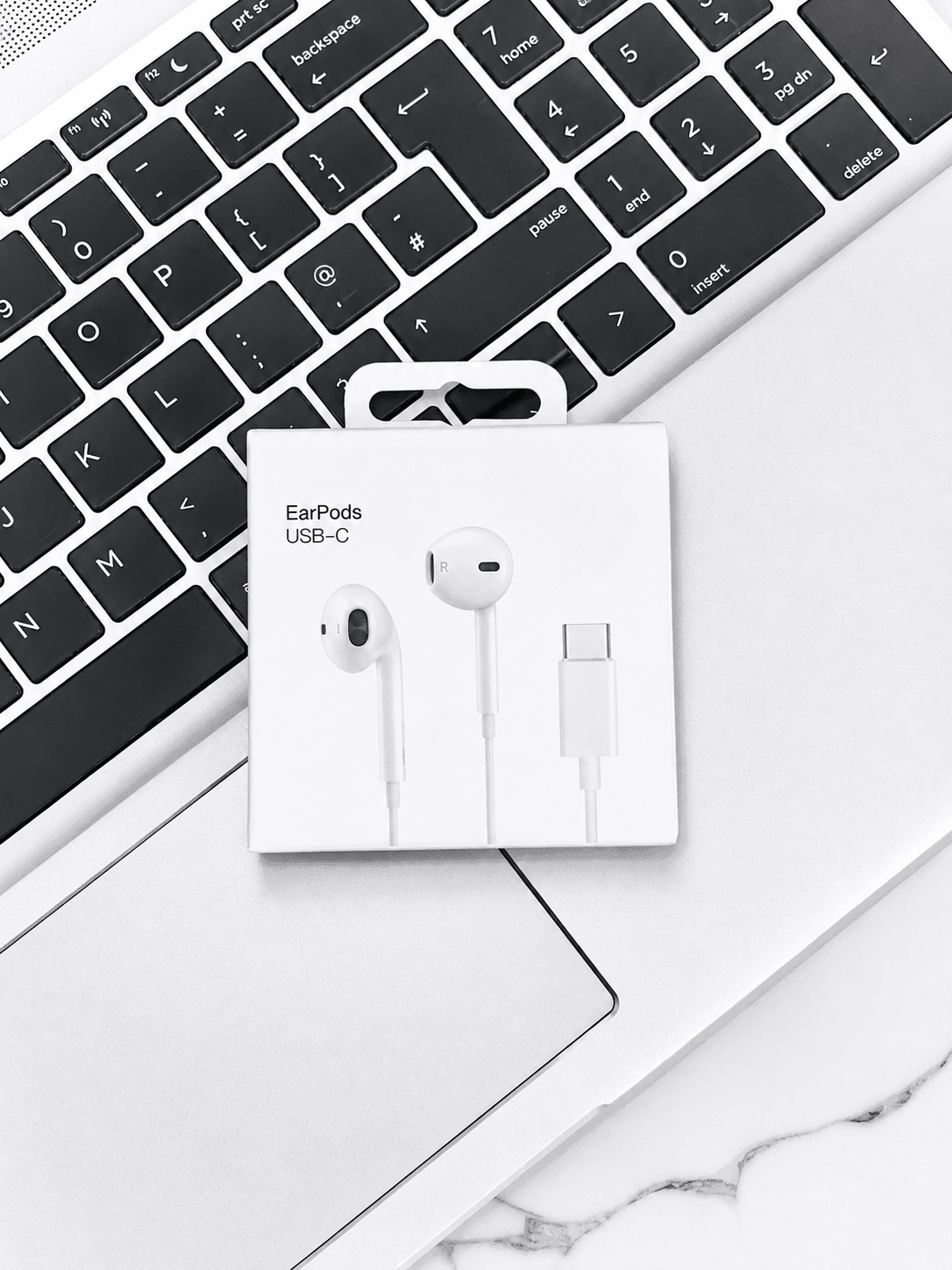 Apple EarPods USB-C headphones in packaging on a laptop keyboard.
