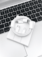 Coiled white USB-C to Lightning charging cable resting on a laptop keyboard