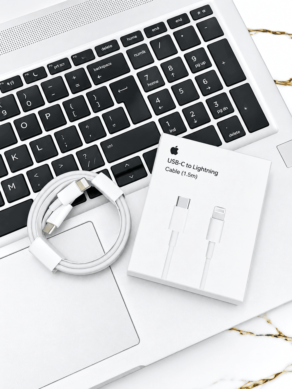 White USB-C to Lightning cable and packaging resting on a laptop keyboard